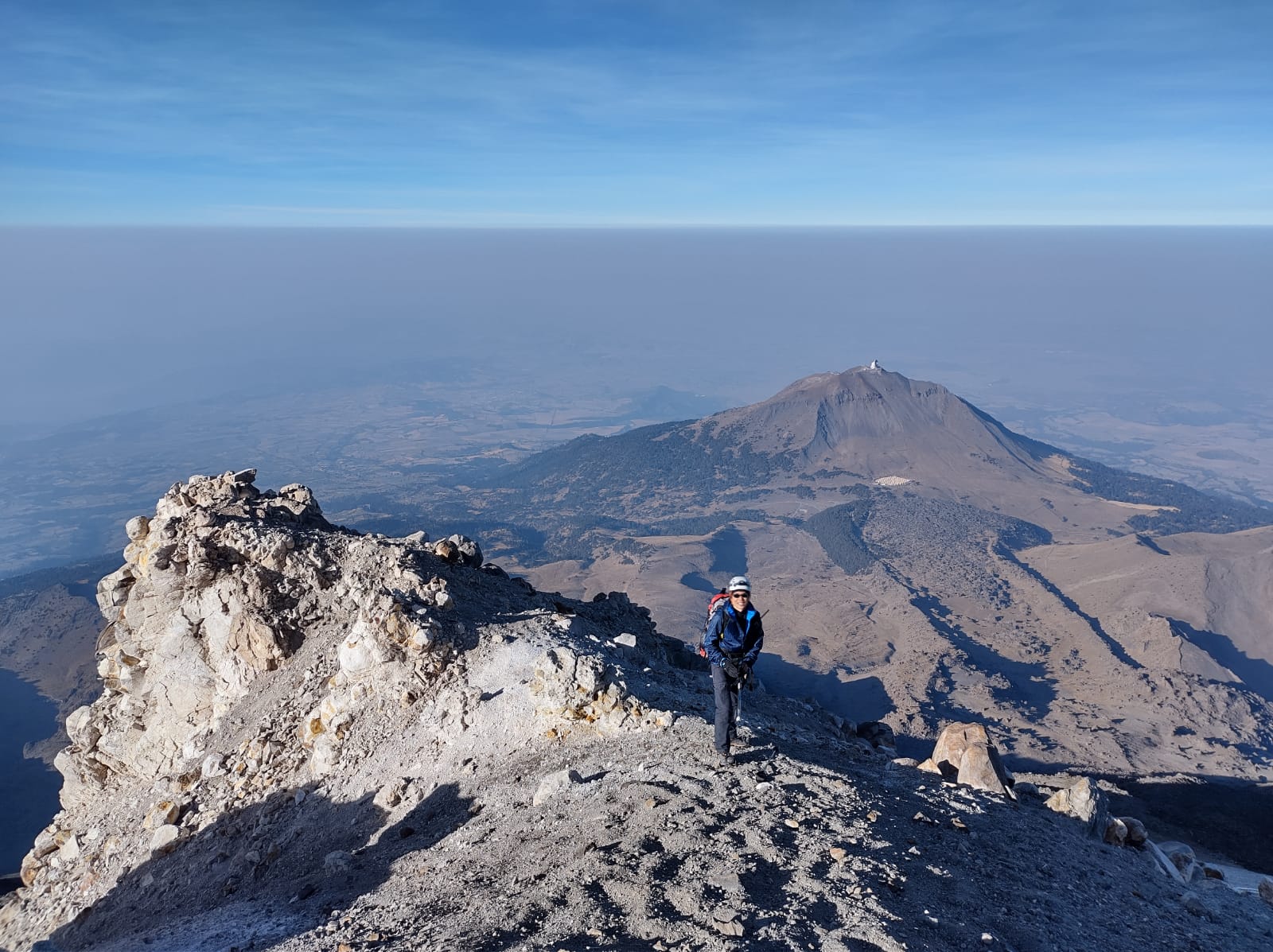 青空をバックに高山でポーズをとるメキシコガイドの岩﨑功